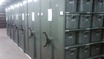Police department evidence storage in bins on mobile shelving system 3, green end panel with chain guard cover