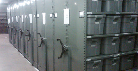 Police department evidence storage in bins on mobile shelving system 3, green end panel with chain guard cover